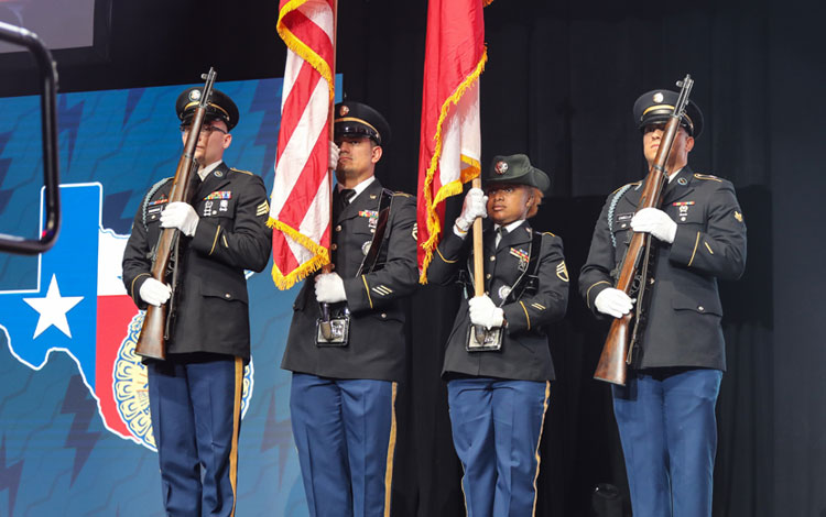 Men in uniform pose while saluting the American Flag